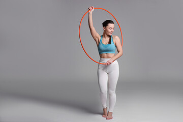 Wall Mural - Beautiful woman with hula hoop on grey background. Space for text