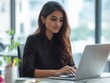 © Alexander Chaykin - A young woman in a modern office setting, engrossed in her laptop work.