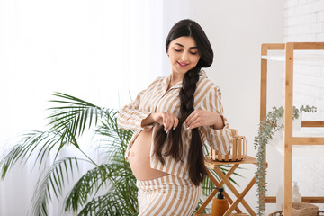 Wall Mural - Beautiful pregnant woman braiding long hair at home