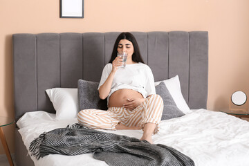 Wall Mural - Beautiful pregnant woman drinking water in bedroom