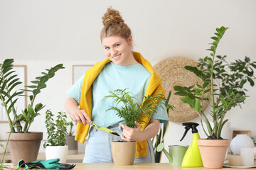 Wall Mural - Young woman taking care of green plants at home