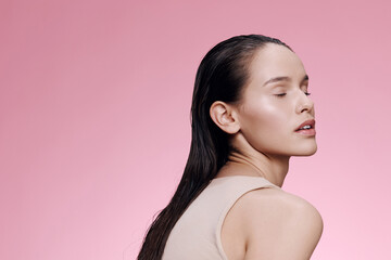 young woman with long hair on a pink background, expressing calmness and confidence, wearing a simpl