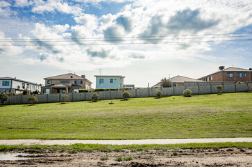 Wall Mural - A row of modern single-family homes lines a wooden boundary fence and sloping hill. A sense of community, real estate housing and comfortable living in an Australian residential neighborhood.