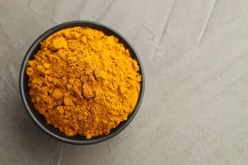 Wall Mural - Turmeric powder in bowl on grey table, top view. Space for text