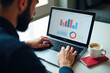© SimpleDesignStudio - Analyzing Financial Trends: A Man Engaged in Data Interpretation While Working on a Laptop in a Bright, Modern Workspace with a Coffee Mug and Notebook