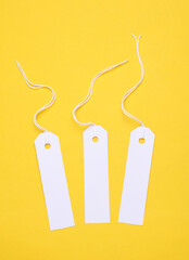 Wall Mural - White paper tags on strings on a yellow background