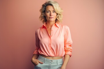 Wall Mural - A woman in a pink shirt and white pants is standing in front of a pink wall