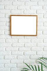 Poster - blank wooden frame on white brick wall with plant in the lower corner capturing minimalism in interi