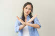 © KMPZZZ - Warning expression negative and serious on face. Asian young woman, female stand making stop, showing gesture hands, doing symbol deny with palm isolated on background at home, perspective forbidden.