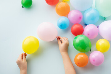 Wall Mural - A child's hand holds a balloon and there are many balloons scattered around on a blue background. The concept of a children's birthday, celebration, party.