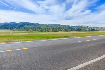 Wall Mural - countryside asphalt road and green meadow with mountain nature landscape on a sunny day. road trip.