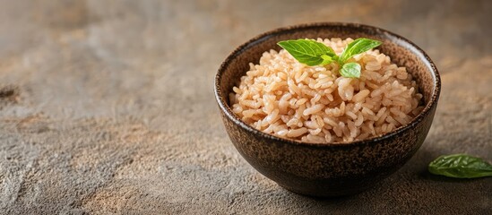 Poster - Brown rice dish in a dark bowl with green mint leaves placed on textured brown background ideal for showcasing healthy Thai snacks.