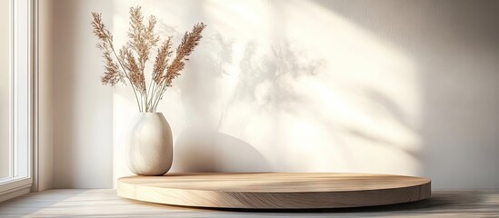 Aufkleber - Minimalist interior scene with a round wooden podium on a light-colored surface, featuring a beige vase and soft shadows from a sunny window.