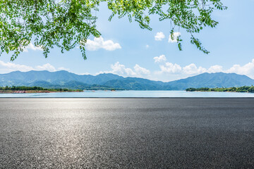 Wall Mural - Asphalt road and blue lake with mountain nature landscape under blue sky