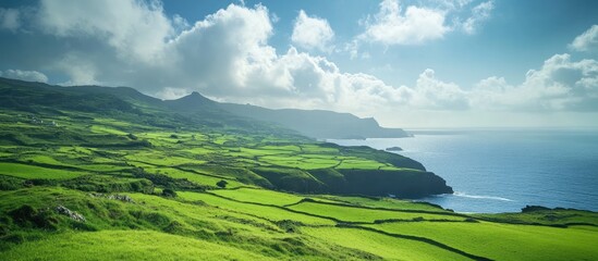 Aufkleber - Lush green hills under a bright blue sky with white clouds, coastal scenery with vibrant greenery and ocean in the background from a panoramic view.