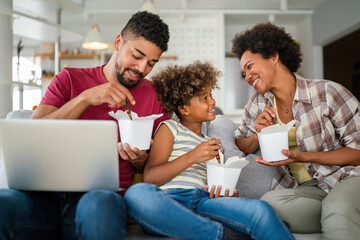 Wall Mural - Happy african family eating at living room and enjoying time together. Home delivary takeaway food