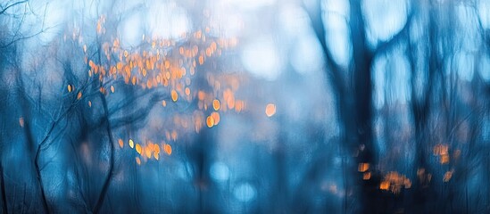 Poster - Misty forest scene with blurred trees in shades of blue and soft orange bokeh lights, creating a serene and tranquil atmosphere.