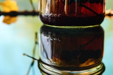 Poster - Elegant jar reflecting vibrant colors of nature outdoors with berries floating inside