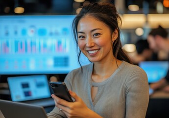 Poster - Smiling woman working in a modern office environment with digital screens, multitasking on a smartphone and laptop for productivity and innovation