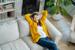 © Yingyaipumi - Happy young asian woman use headphones and relaxing at home.Female smile sitting on sofa,couch and holding mobile smartphone.Listening to music on lazy and radiating joy and relaxation.