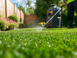 © Muh Saleh - Gardener spraying artificial lawn, backyard, sunny day, home maintenance