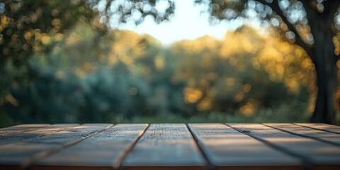 Wall Mural - Wooden tabletop with detailed texture in the foreground, soft blurred nature background with golden autumn hues and lush greenery in the distance.