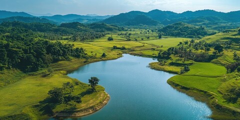 Aufkleber - Vast green landscape with a serene blue lake reflecting mountains under a bright sky, featuring lush fields and palm trees in the foreground.