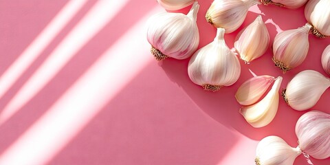 Poster - Fresh garlic bulbs and cloves arranged on a soft pink background with diagonal shadows creating a warm ambiance across the scene.