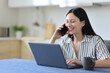 © Antonioguillem - Happy asian woman talking on phone checking laptop