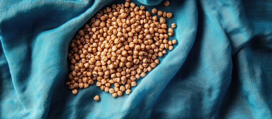 Poster - Buckwheat grains scattered on a textured blue fabric creating a vibrant and natural food backdrop for culinary or health-related themes.
