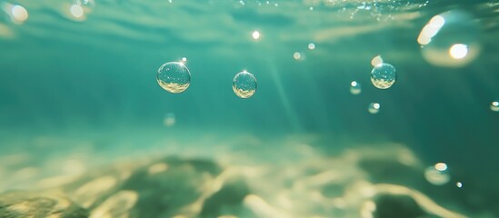 Poster - Close up of underwater bubbles in clear turquoise ocean water with a bokeh effect and sunlight filtering through the surface creating a serene atmosphere