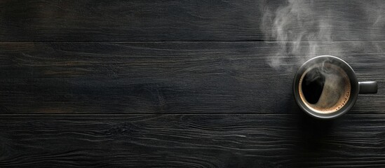 Poster - Coffee cup with steam on dark wooden floor top view with space for text inviting a cozy morning vibe and relaxation atmosphere.