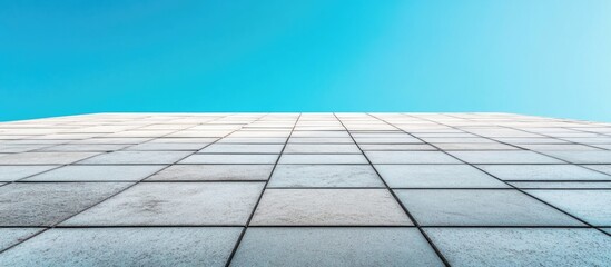 Aufkleber - Concrete tiles arranged in symmetrical lines against a vibrant blue sky creating a modern architectural perspective.