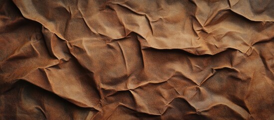 Fototapete - Textured crumpled light brown leather surface with intricate folds and wrinkles highlighting its aged and vintage appeal