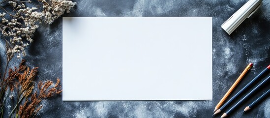 Poster - Creative workspace with blank paper surrounded by pens pencils and dried flowers for artistic design or marketing concepts.