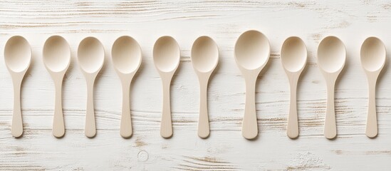 Poster - Design mockup of empty beige wooden spoons arranged on a white wooden background with ample copy space for culinary or branding use