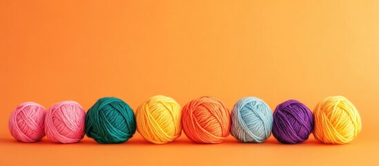 Poster - Colorful yarn balls displayed in a neat row on a vibrant orange background with ample empty space for creative text placement.