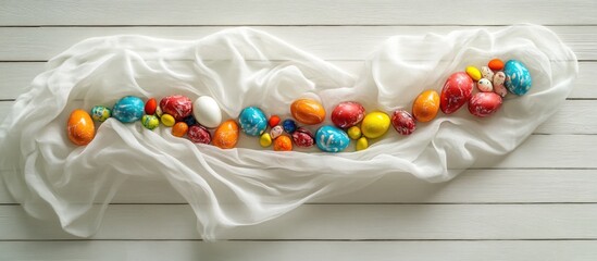 Poster - Easter Celebration Background with Colorful Eggs and Sweets on White Fabric Over Wooden Surface