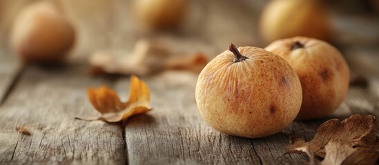 Poster - Dried quinces placed on a rustic wooden surface with autumn leaves, evoking a warm and cozy seasonal atmosphere