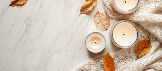 Fototapete - Cozy autumn flat lay featuring candles, dried leaves, and a soft sweater with ample space for text or branding.