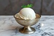 © Balaraw - A scoop of vanilla ice cream in a silver bowl topped with mint.