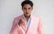 © zong - Stylish portrait of a young handsome man in pink suit making mini heart gesture with cheerful smile against white background