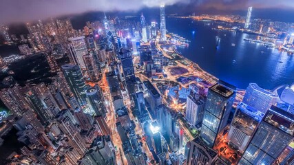 Poster - 4K video zoom in Hong Kong night. Aerial view of glowing city skyscrapers and harbor direction from above.