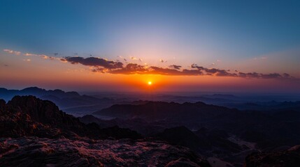 Aufkleber - Breathtaking sunset unfolds over a vast desert, painting the sky in vibrant hues of orange and purple. The sun dips behind jagged mountain peaks, casting long shadows across the horizon