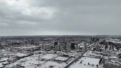 Wall Mural - Drone footage of snow-covered city skyline under gray cloudy sky in Waterloo, Ontario, Canada