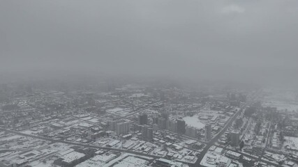 Wall Mural - Drone footage of ice-covered city under snowfall and dense fog during a deep winter season