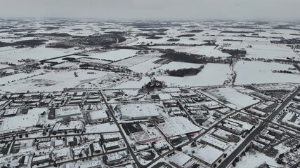 Wall Mural - Drone footage of snow-covered district under a foggy sky with frozen rural fields in the background