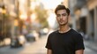 © Justice - A young man in a black t-shirt stands confidently on a city street, his gaze directed forward. The sun casts a warm, golden hue over the scene, highlighting the man's sharp features and the texture of