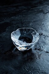 Poster - Crystal bowl containing clear water rests on a jet-black surface. Soft light reflections create a sophisticated, exclusive atmosphere that enhances the serene mood