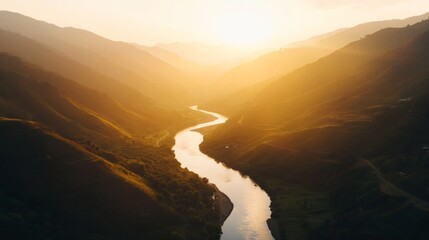 Poster - Aerial view showcases a vibrant mountain range with glowing twilight hues while a gentle river winds through the landscape, reflecting the warmth of the setting sun
